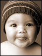 Маленький мальчуган в детской шапочке показывает получателю открытки забавную улыбку.