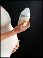 Молодая беременная мама держит в руках маленькую бутылочку с материнским молоком, с пополнением.