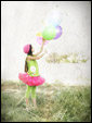 Маленькая девочка держит в руках воздушные шарики и, отпуская их в небеса, загадывает желание на День Рождения!