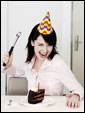 Девушка с молотком собирается забить праздничную свечку в торт.