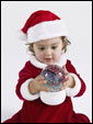Маленькая девочка смотрит на рождественский шар, как бы говоря: Чудеса происходят: только верь!