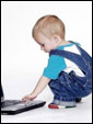 Маленький мальчик водит пальцем по тачпэду ноутбука.