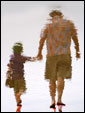Отражение отца и дочери, идущих держась за руки по берегу озера. Спасибо, папа, за личный пример!