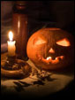 На столе при свете свечи светится тыква - символ Хэллоуина, знак приглашения демонических сил в свой дом.
