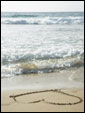 Берег моря, нарисованное на песке сердечко и надпись: Есть чувства, которые овладевают всем моим естеством, оставляя меня безоружным... Любовь - главное из них!