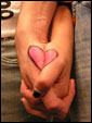 Парень и девушка, взявшись за руки, образовали изображение сердечка, символизирующего любовь.