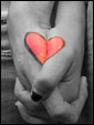 Молодая пара крепко держит друг друга за руки, на которых нарисованы две половинки сердца.