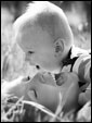Молодая мама резится со своим малышем на озаренной солнцем лужайке, ведь всё лучшее в человеке - от лучей солнца и молока матери.