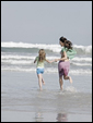 Маленькая девочка бежит по берегу океана, держась за руку своей матери: Мамочка, с тобой всегда так хорошо!
