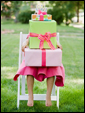 Маленькая принцесса держит на своих коленях целую стопку подарков - а как могло быть иначе!