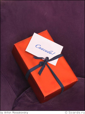 Лежащий на софе маленький подарок с запиской, выражает собой благодарность отправителя.