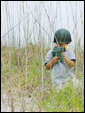 Мальчик с автоматом прячется в кустах на берегу реки, проявляя свой мужской характер.